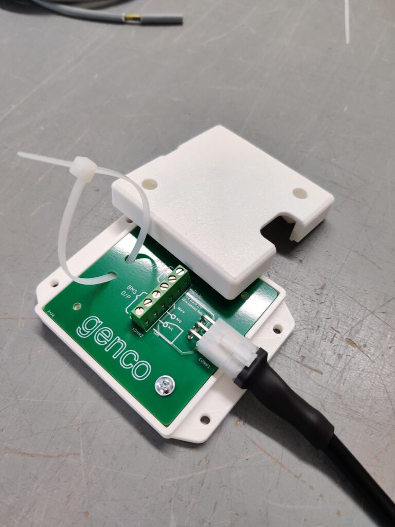 Green circuit board mounted on a white plastic enclosures with a black cable connected.