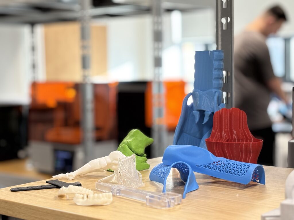 Various coloured 3D printed health-related pretotypes displayed on a workshop bench.